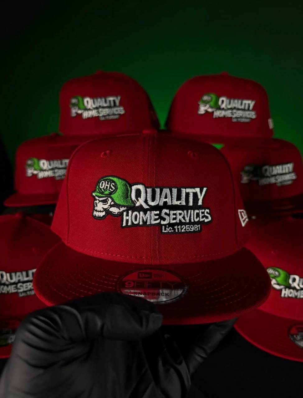 Red New Era 9FIFTY snapbacks with the Quality Home Services logo stitched on the front